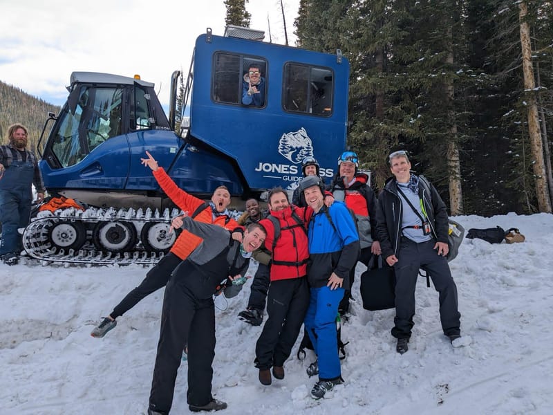 Chris Carey and a group of friends in the snow beside a blue snowcat